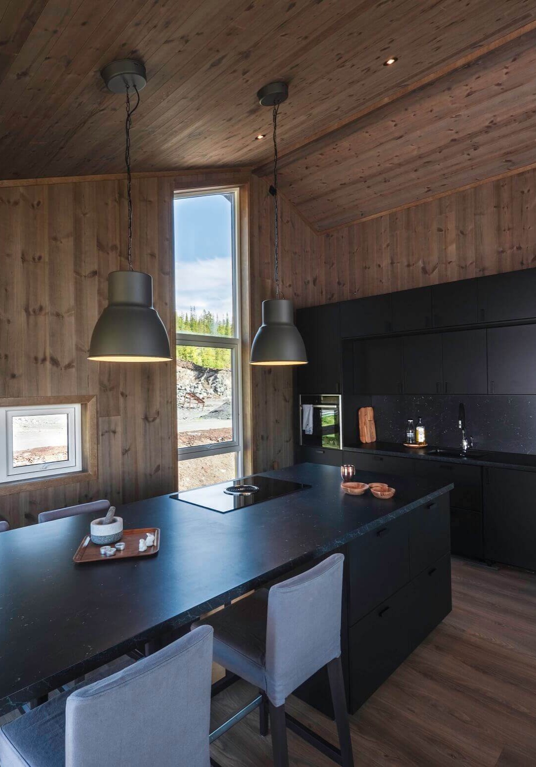 Kjøkkenøy med sort benkeplate og sorte fronter. Foto.